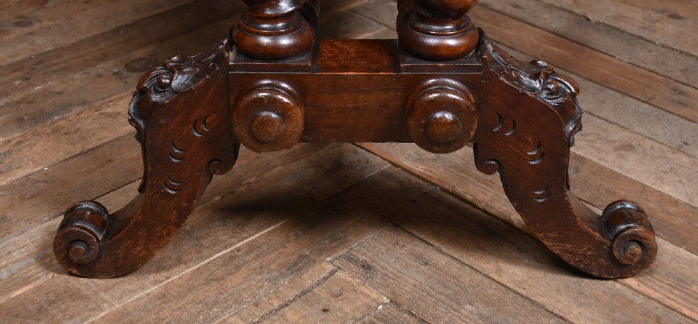 A Victorian carved dark oak writing table featuring a central Green Man mask, inset leather writing surface, and barley twist stretchers. View XV