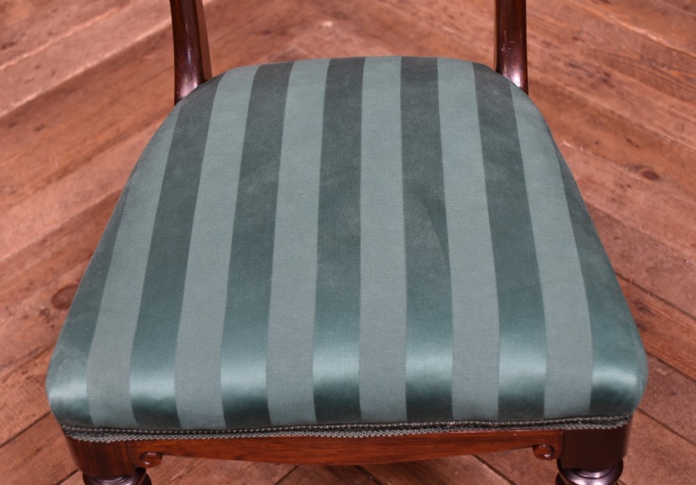 A set of six Victorian rosewood dining chairs featuring carved crest rails, decorative mid-rails, fluted turned front legs, and green striped upholstered seats. View VII