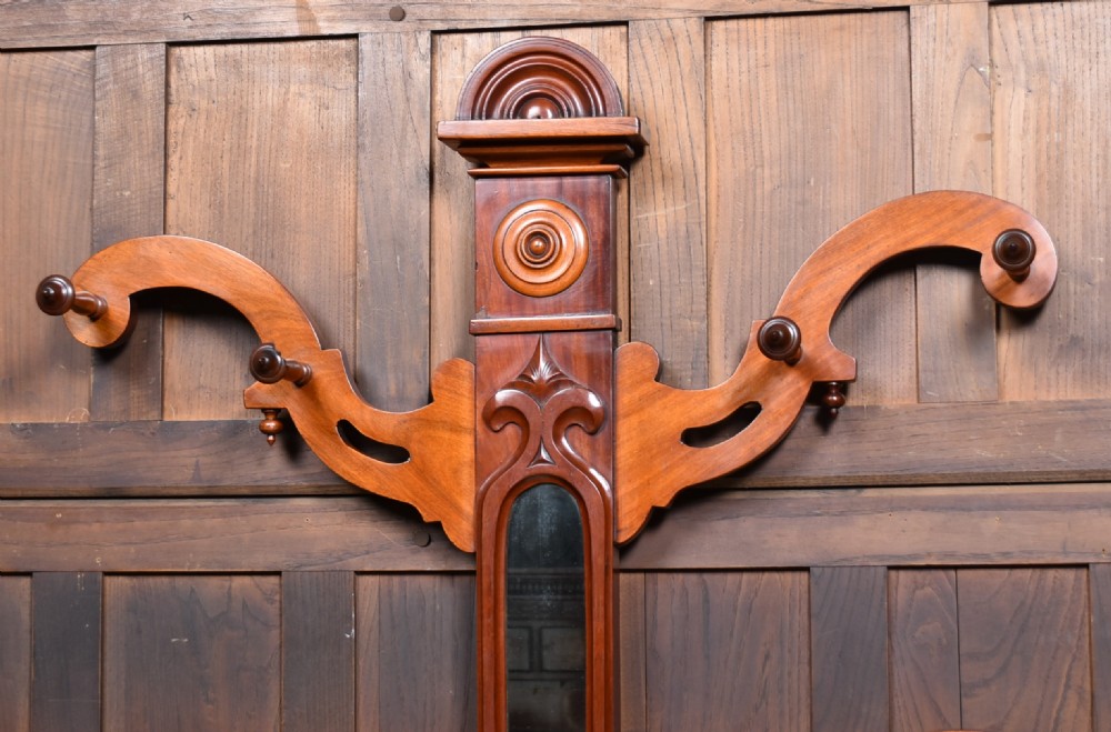 A Victorian mahogany hall stand featuring carved coat hooks, a central narrow mirror, a marble top over a single drawer, and integrated umbrella stands with drip trays. View II