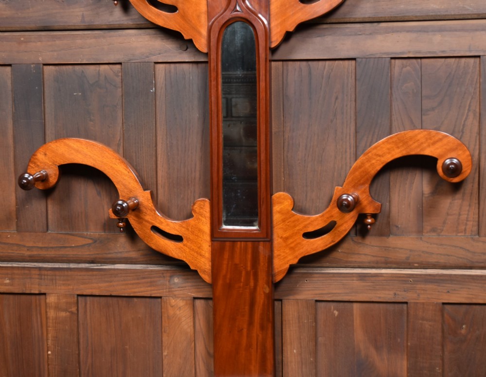 A Victorian mahogany hall stand featuring carved coat hooks, a central narrow mirror, a marble top over a single drawer, and integrated umbrella stands with drip trays. View III