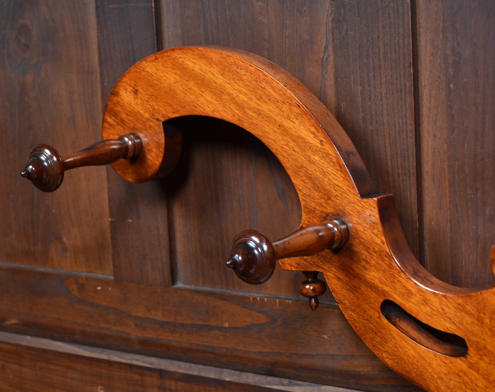 A Victorian mahogany hall stand featuring carved coat hooks, a central narrow mirror, a marble top over a single drawer, and integrated umbrella stands with drip trays. View VI