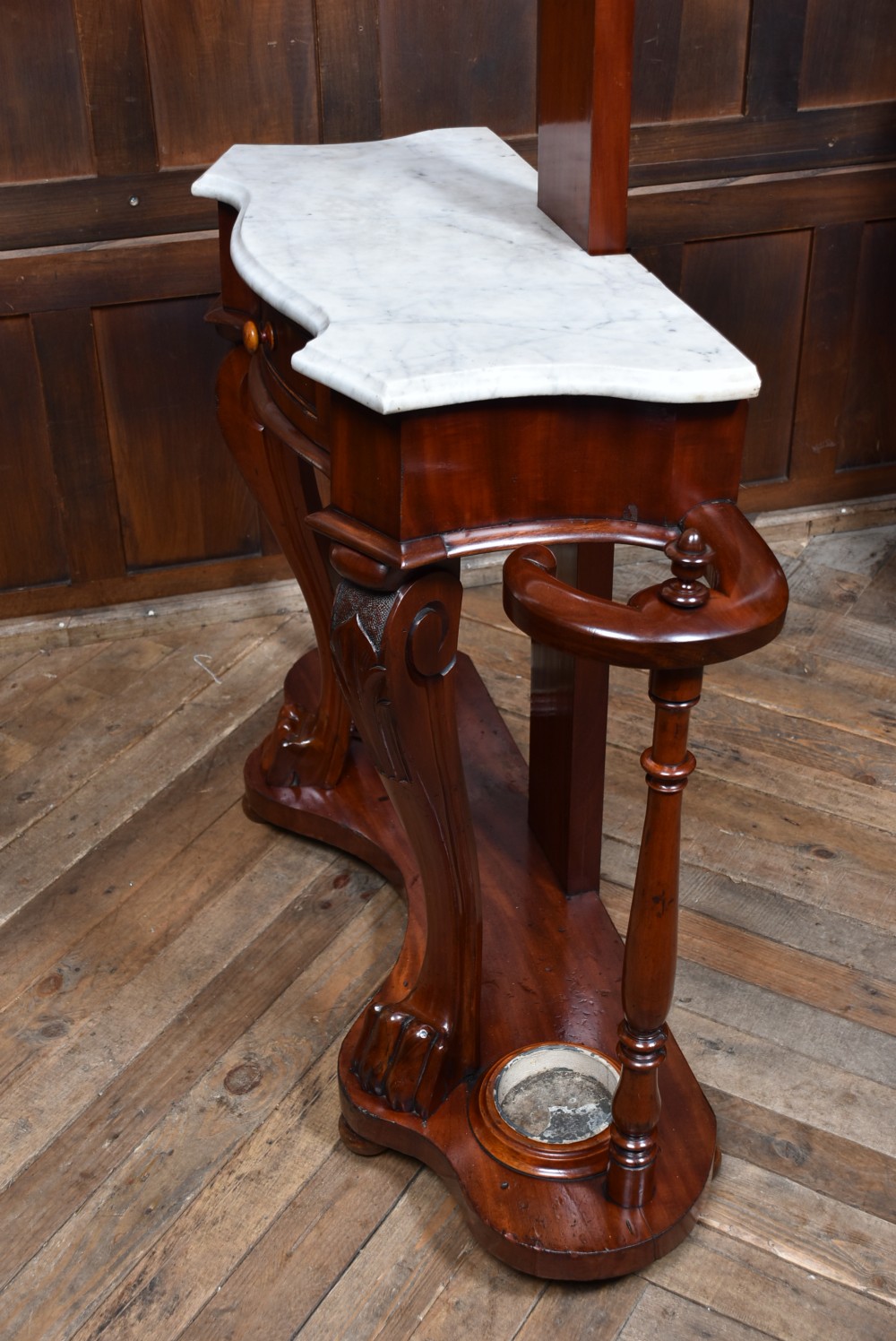 A Victorian mahogany hall stand featuring carved coat hooks, a central narrow mirror, a marble top over a single drawer, and integrated umbrella stands with drip trays. View XVI