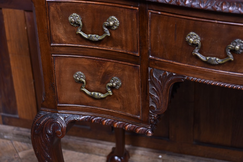 An Edwardian mahogany writing desk featuring a leather inset top, carved cabriole legs with ball-and-claw feet, and five drawers with brass swan-neck handles. View VI