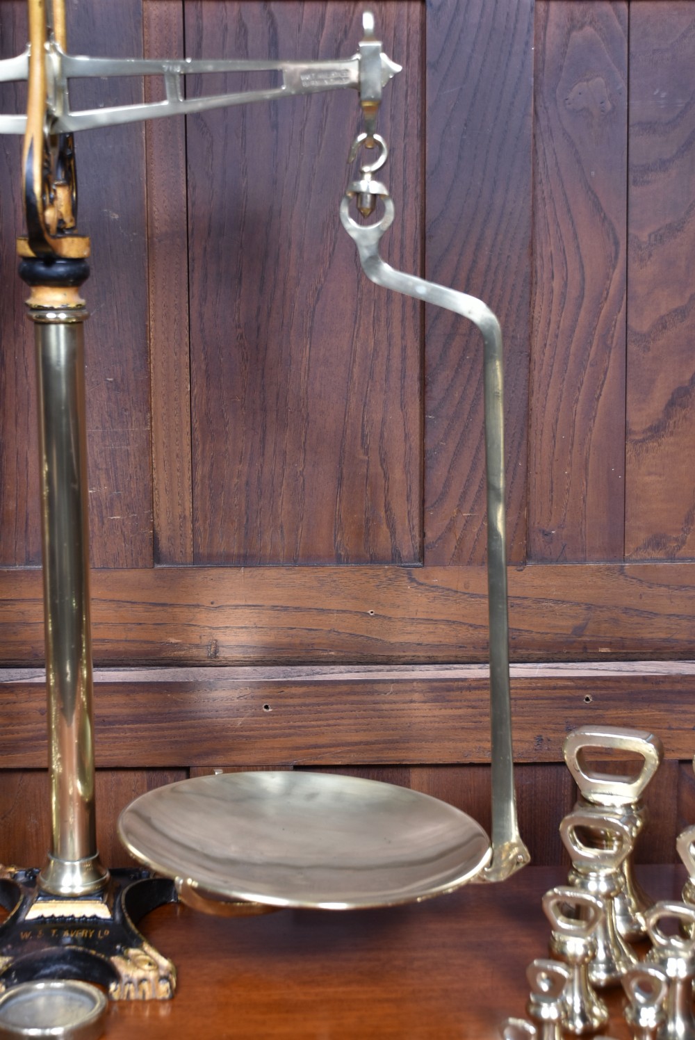 An Edwardian brass shopkeeper balance scale set on a central column base with two suspended pans and matching brass weights. View III