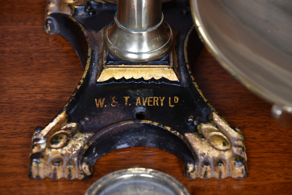An Edwardian brass shopkeeper balance scale set on a central column base with two suspended pans and matching brass weights. View VII
