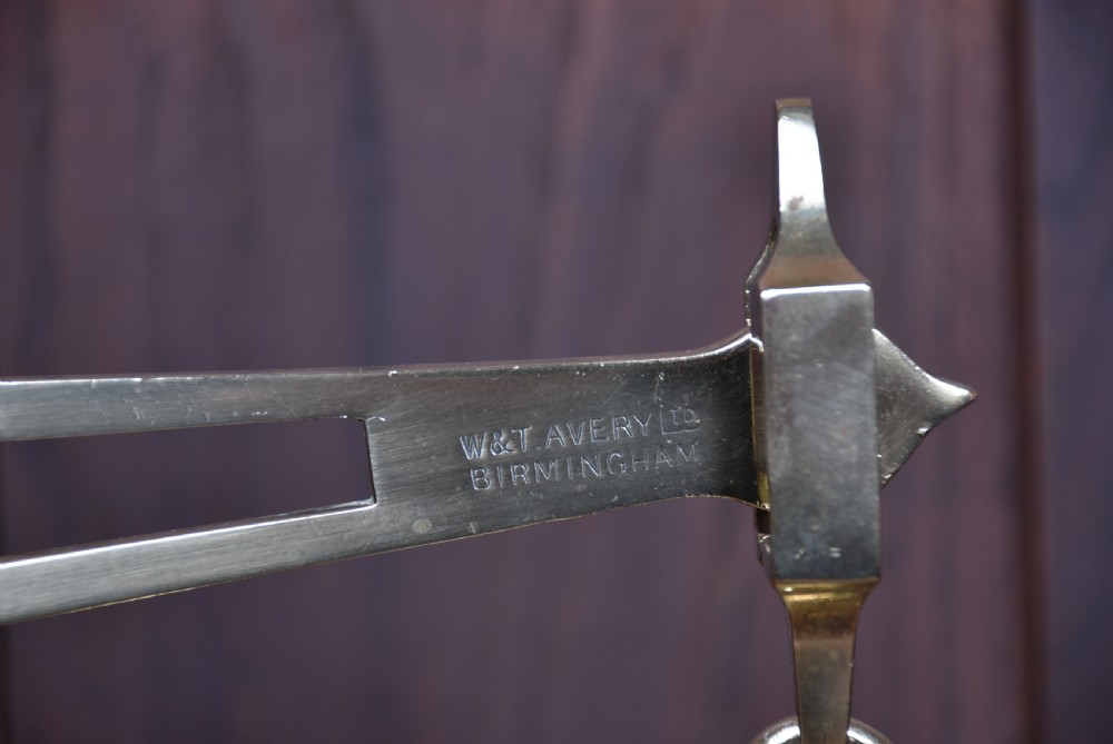 An Edwardian brass shopkeeper balance scale set on a central column base with two suspended pans and matching brass weights. View IX