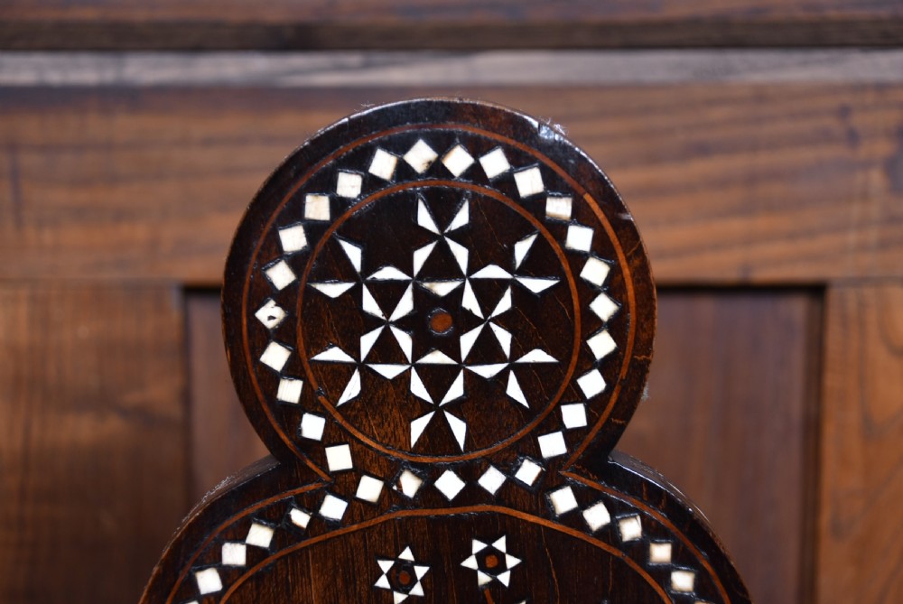 A pair of dark wood armchairs intricately decorated with white geometric bone inlay throughout the backrests, seats, arms, and legs. View VI