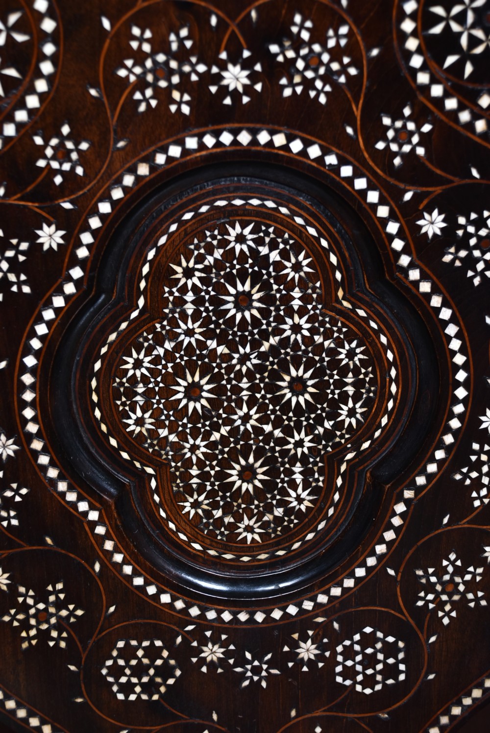 A pair of dark wood armchairs intricately decorated with white geometric bone inlay throughout the backrests, seats, arms, and legs. View VII