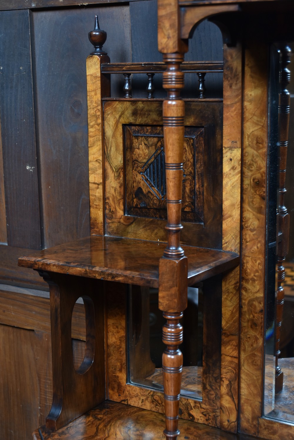 A late Victorian burr walnut display cabinet featuring tiered shelving, multiple mirror panels, turned support pillars, and carved lower cabinet doors. View VII