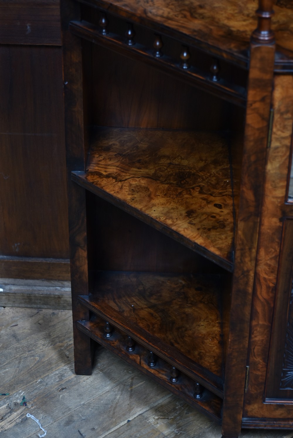 A late Victorian burr walnut display cabinet featuring tiered shelving, multiple mirror panels, turned support pillars, and carved lower cabinet doors. View X