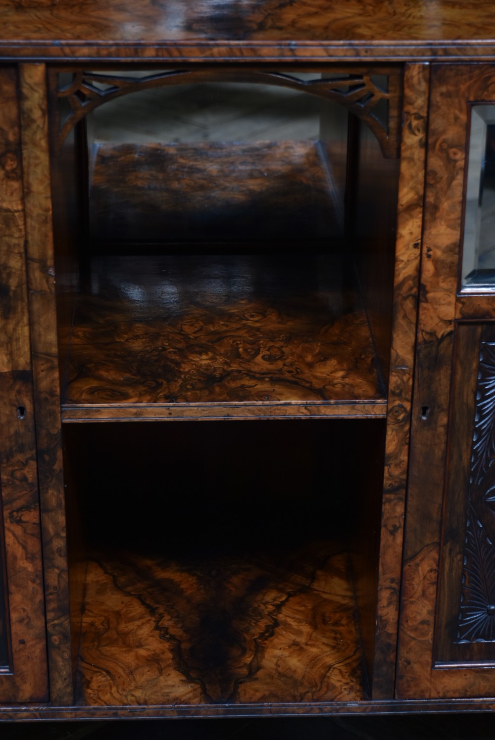 A late Victorian burr walnut display cabinet featuring tiered shelving, multiple mirror panels, turned support pillars, and carved lower cabinet doors. View XIII