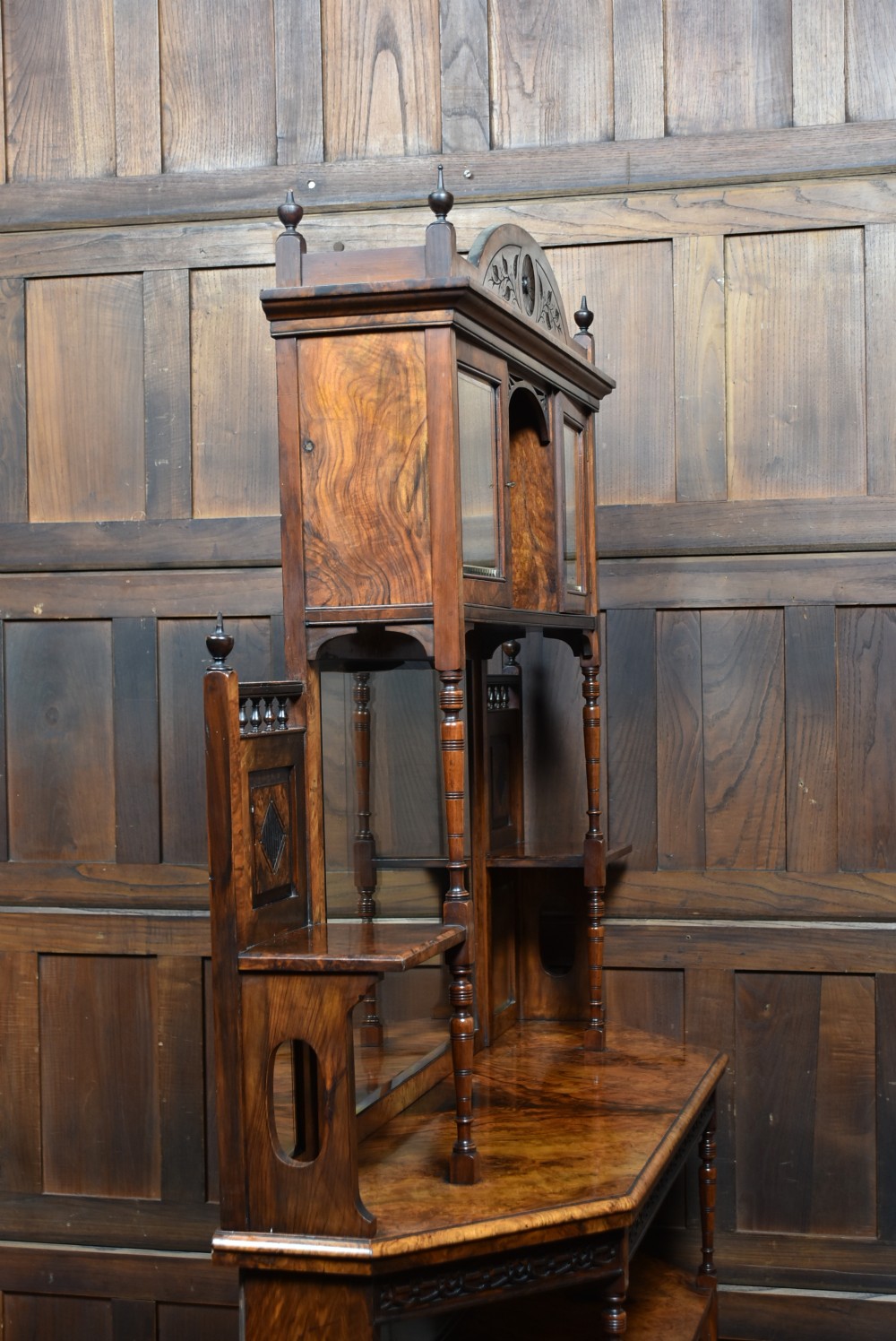 A late Victorian burr walnut display cabinet featuring tiered shelving, multiple mirror panels, turned support pillars, and carved lower cabinet doors. View XV