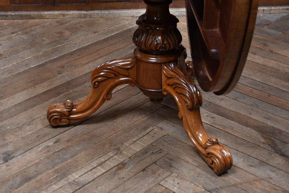 A Victorian rosewood snap-top supper table with a polished circular top tilted vertically on a carved tripod base. View VII