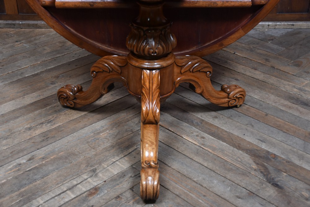 A Victorian rosewood snap-top supper table with a polished circular top tilted vertically on a carved tripod base. View X