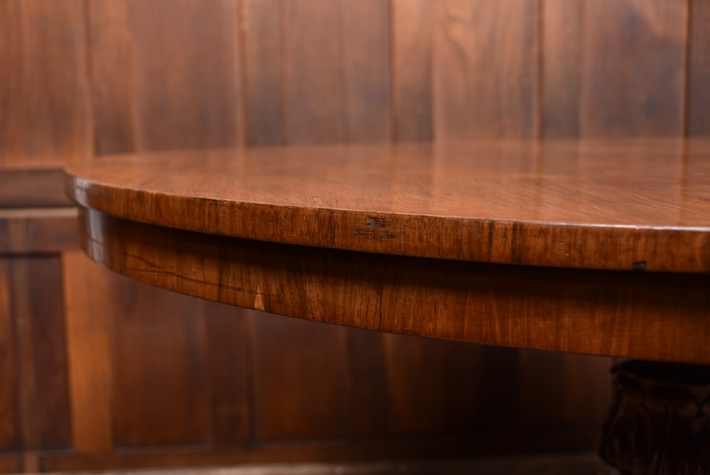 A Victorian rosewood snap-top supper table with a polished circular top tilted vertically on a carved tripod base. View XIV