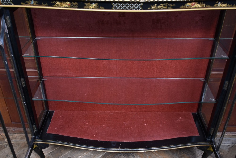 An Edwardian black lacquered display cabinet featuring hand-painted gold Chinoiserie motifs, arched astragal glazing, and cabriole legs. View XX