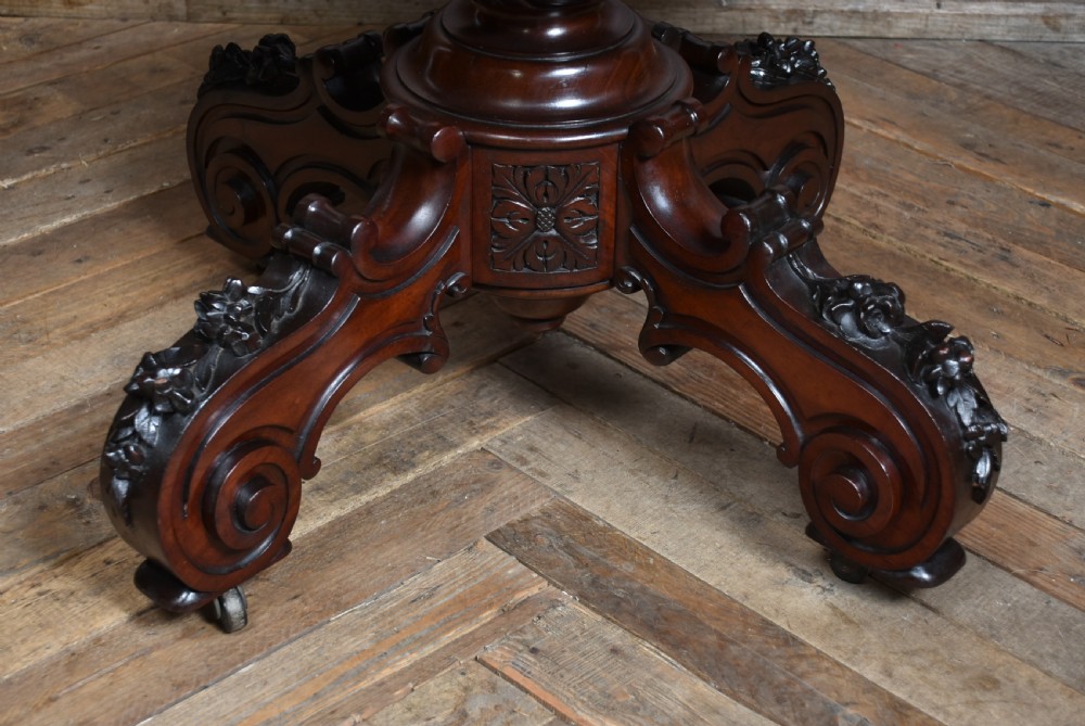 A Victorian walnut centre table featuring a violin-shaped contoured top, a central carved bulbous pedestal column, and four scrolled cabriole legs on brass castors. View VIII