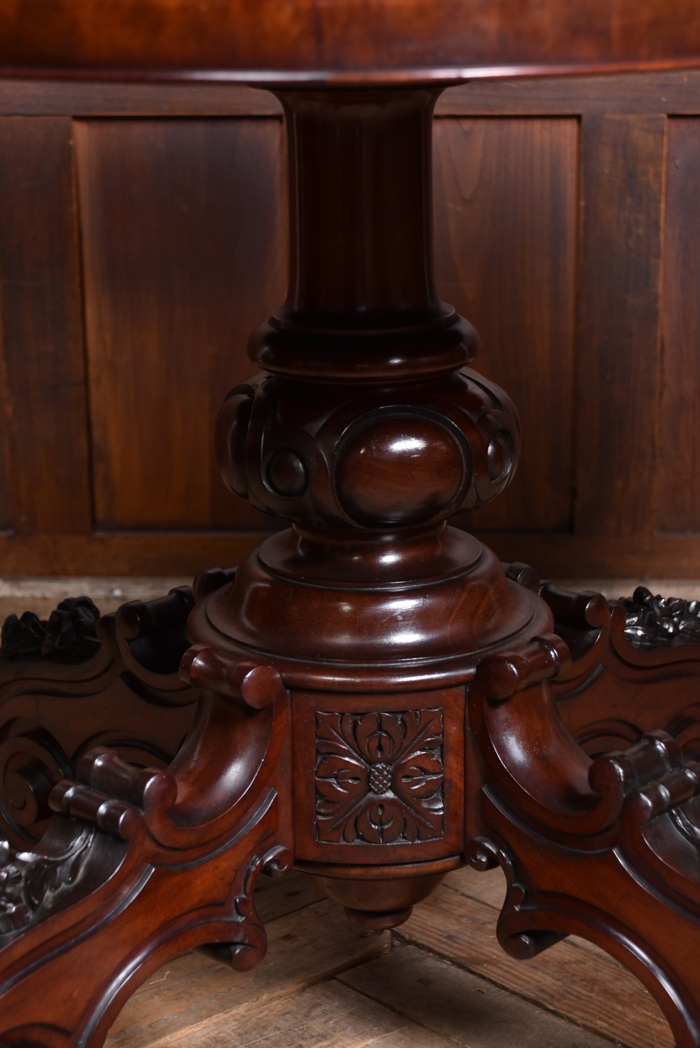 A Victorian walnut centre table featuring a violin-shaped contoured top, a central carved bulbous pedestal column, and four scrolled cabriole legs on brass castors. View IX