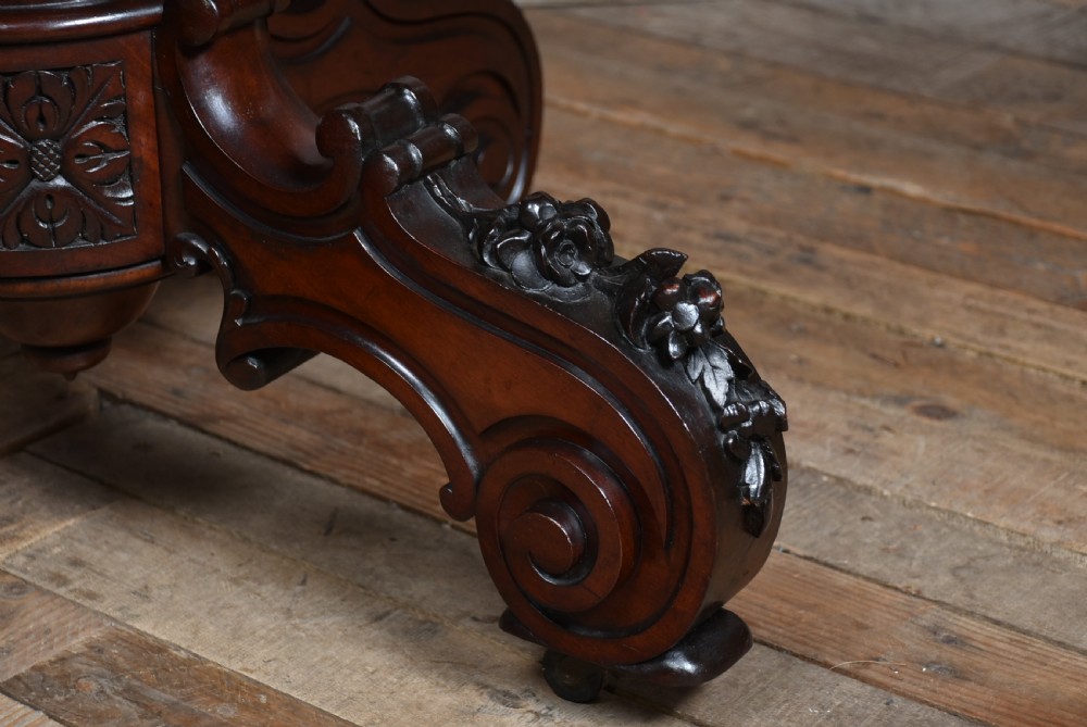 A Victorian walnut centre table featuring a violin-shaped contoured top, a central carved bulbous pedestal column, and four scrolled cabriole legs on brass castors. View XI