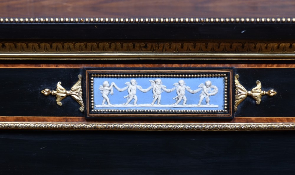 A Victorian ebonised and amboyna breakfront credenza featuring a central cupboard with a blue jasperware plaque flanked by open shelves and gilt fluted columns. View VII