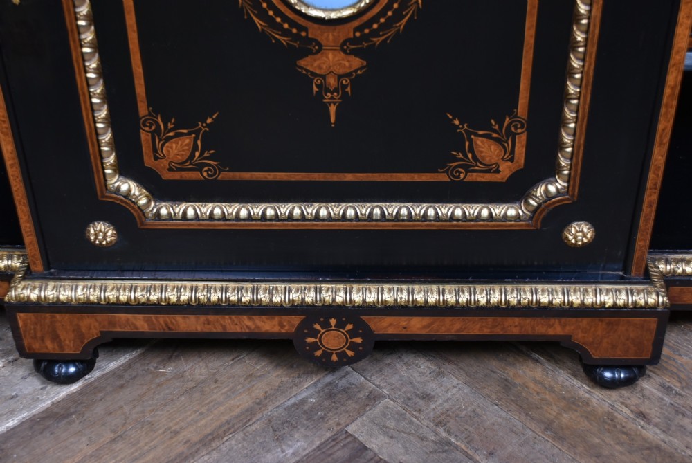 A Victorian ebonised and amboyna breakfront credenza featuring a central cupboard with a blue jasperware plaque flanked by open shelves and gilt fluted columns. View X
