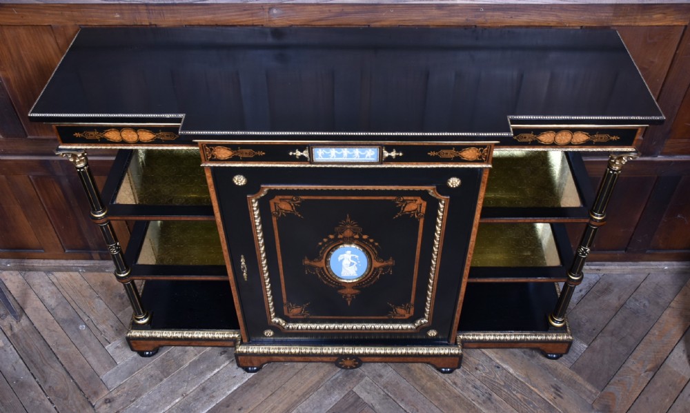 A Victorian ebonised and amboyna breakfront credenza featuring a central cupboard with a blue jasperware plaque flanked by open shelves and gilt fluted columns. View XII