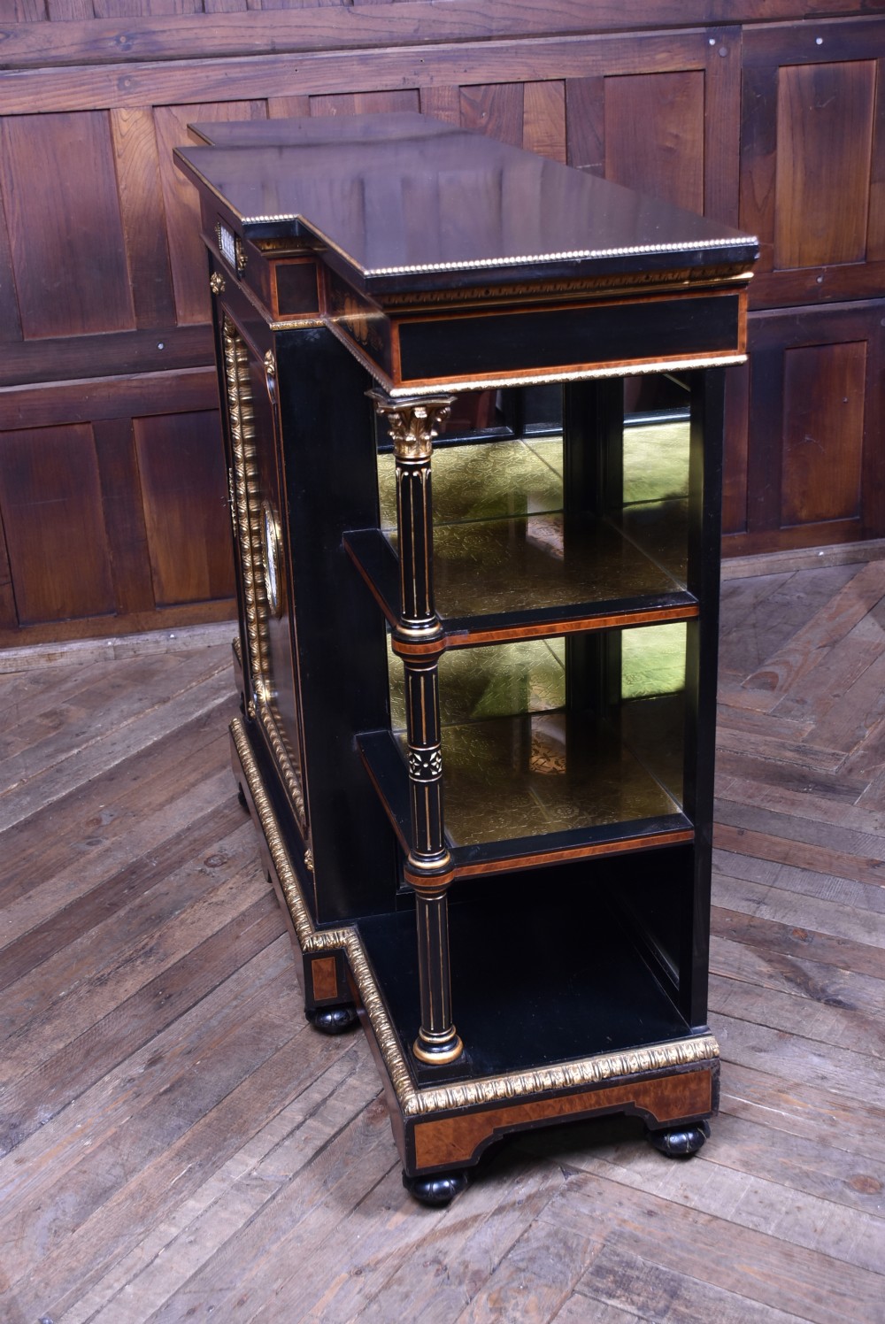A Victorian ebonised and amboyna breakfront credenza featuring a central cupboard with a blue jasperware plaque flanked by open shelves and gilt fluted columns. View XVII