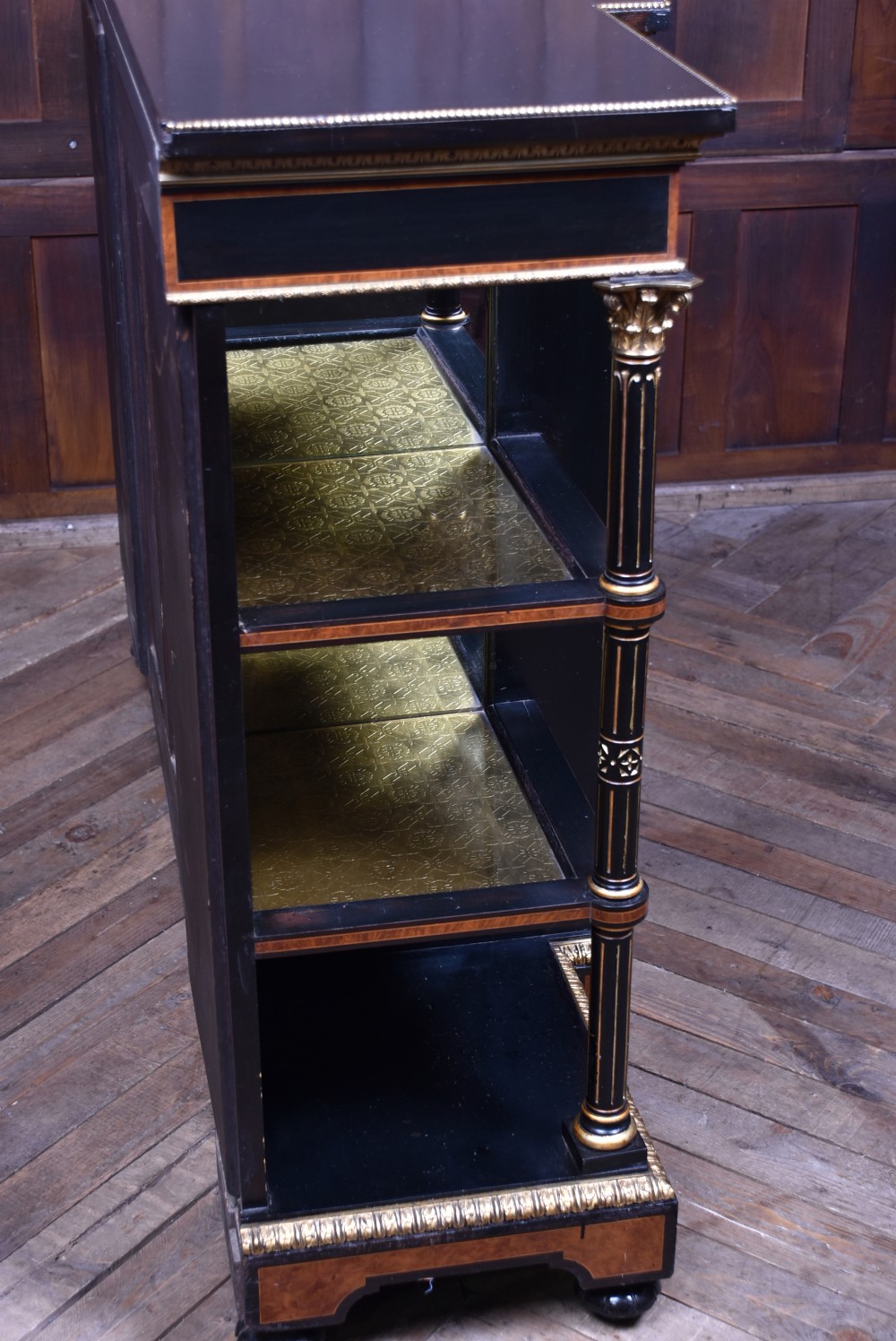 A Victorian ebonised and amboyna breakfront credenza featuring a central cupboard with a blue jasperware plaque flanked by open shelves and gilt fluted columns. View XXI