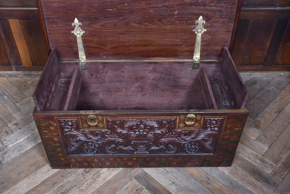 A dark reddish brown padouk wood storage chest featuring a relief-carved floral front panel and decorative brass metal mounts across the top lid and frame. View XIII