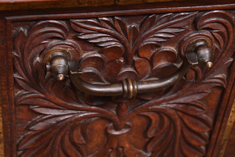 A dark reddish brown padouk wood storage chest featuring a relief-carved floral front panel and decorative brass metal mounts across the top lid and frame. View XVII