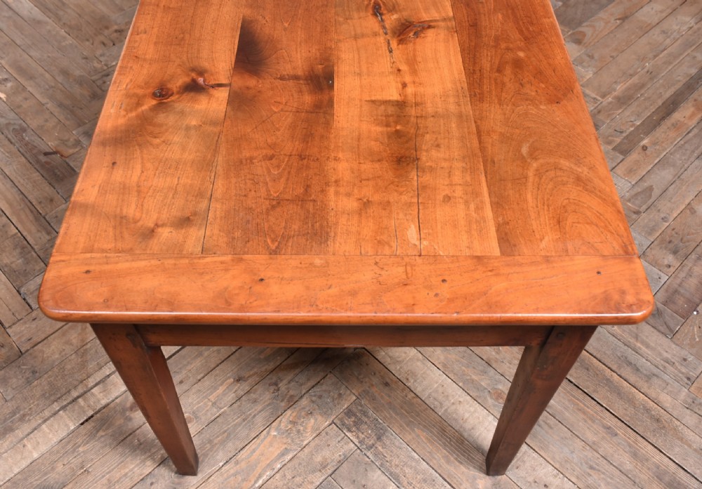 A long antique French cherry wood farmhouse table featuring tapered legs, a single side drawer with a metal cup handle, and a plank top with framed borders. View V