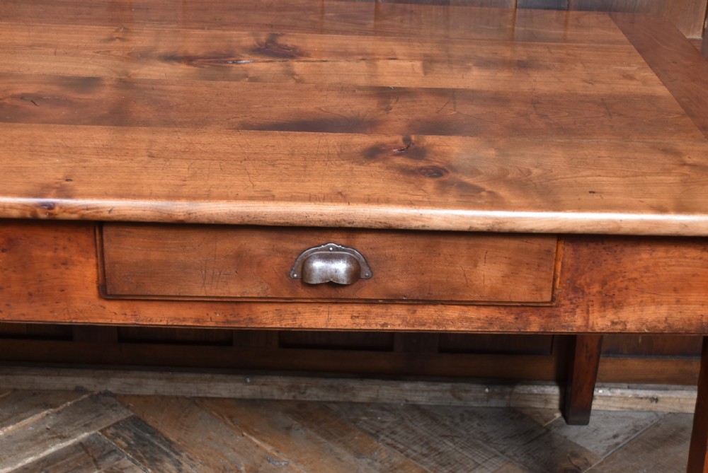 A long antique French cherry wood farmhouse table featuring tapered legs, a single side drawer with a metal cup handle, and a plank top with framed borders. View IX
