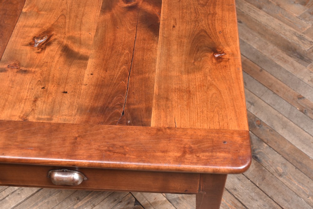 A long antique French cherry wood farmhouse table featuring tapered legs, a single side drawer with a metal cup handle, and a plank top with framed borders. View XV