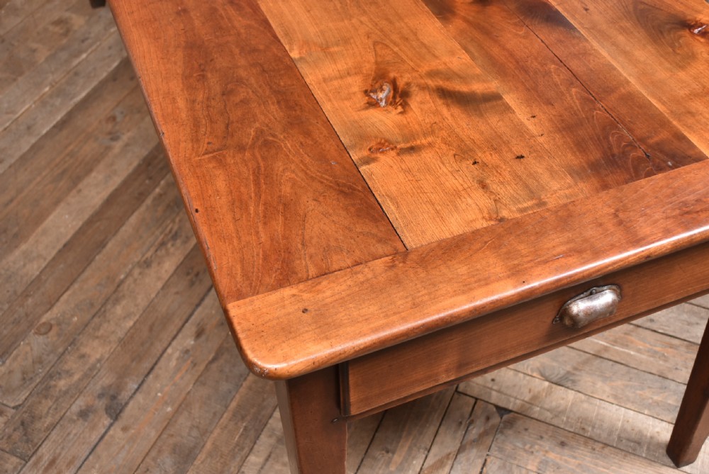 A long antique French cherry wood farmhouse table featuring tapered legs, a single side drawer with a metal cup handle, and a plank top with framed borders. View XVI
