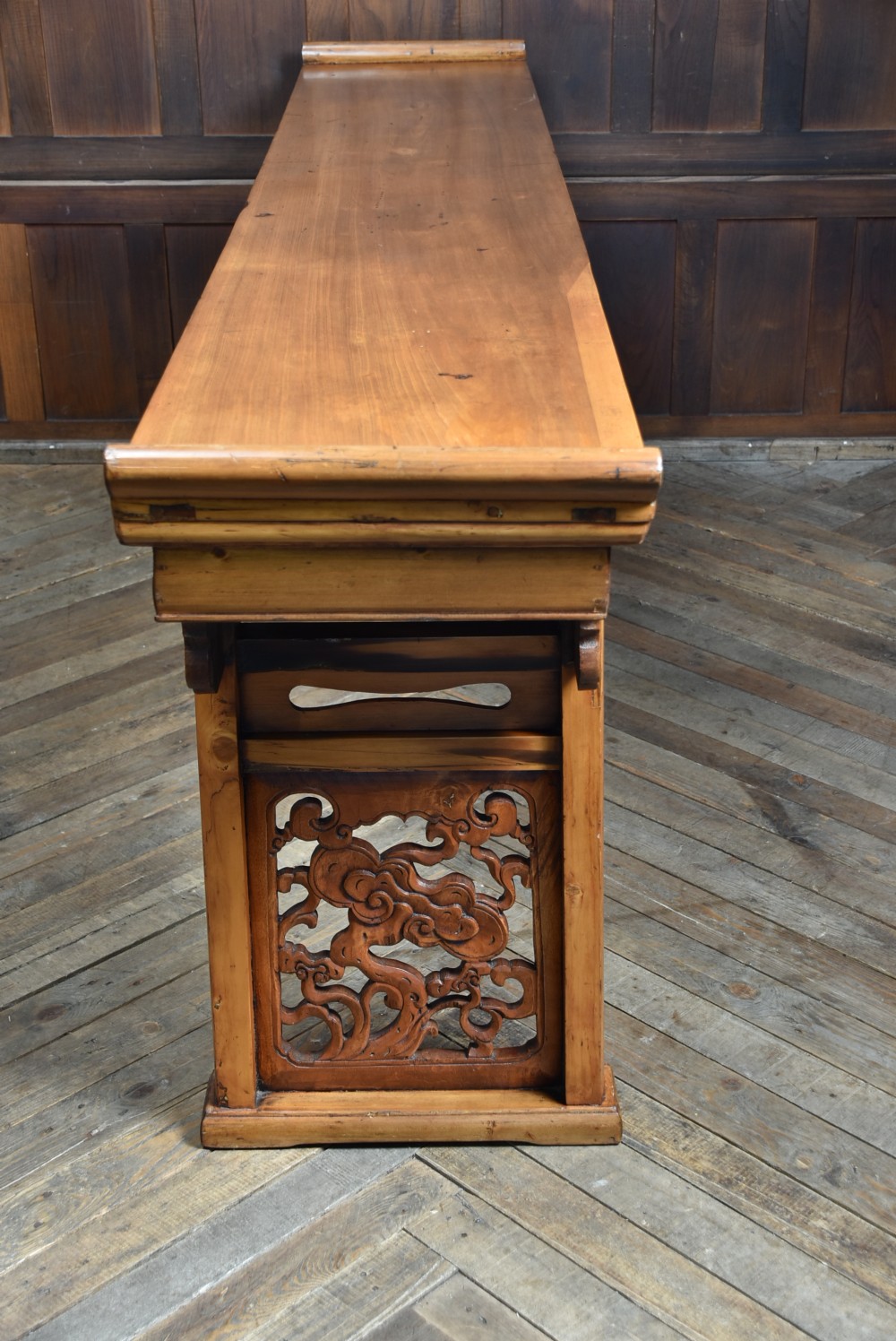 A long, light honey brown timber Chinese altar console table featuring upturned flange ends and carved decorative spandrels. View VII