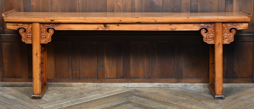 A long, light honey brown timber Chinese altar console table featuring upturned flange ends and carved decorative spandrels. View VIII