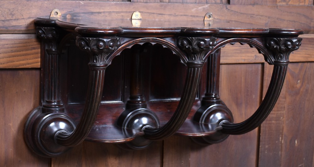 A Victorian dark rosewood carved wall bracket shelf featuring three fluted columns with carved capitals and scalloped arches. View III