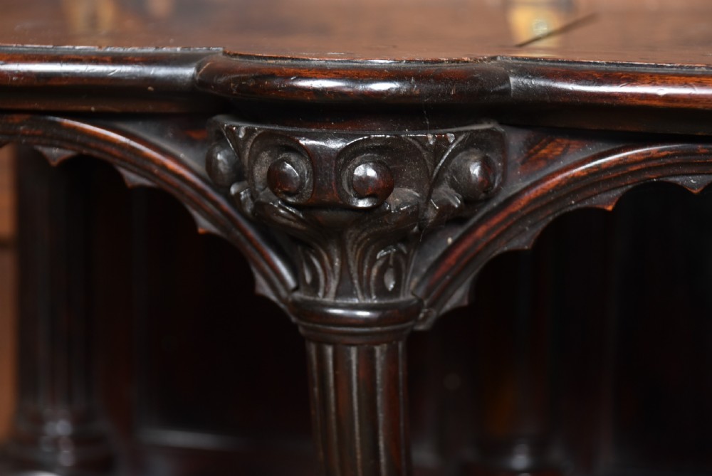 A Victorian dark rosewood carved wall bracket shelf featuring three fluted columns with carved capitals and scalloped arches. View VII