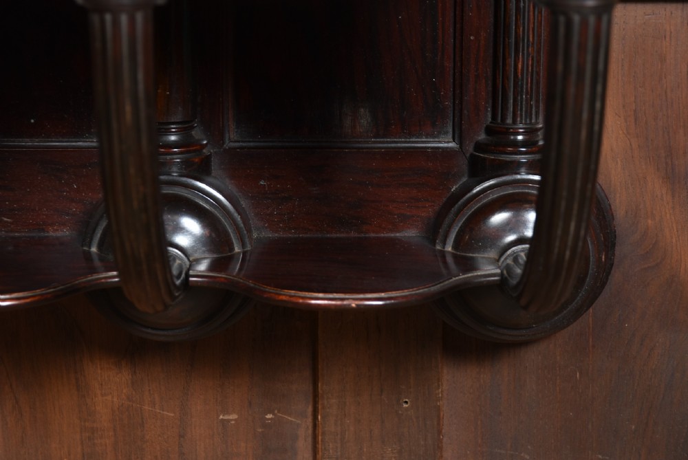 A Victorian dark rosewood carved wall bracket shelf featuring three fluted columns with carved capitals and scalloped arches. View VIII