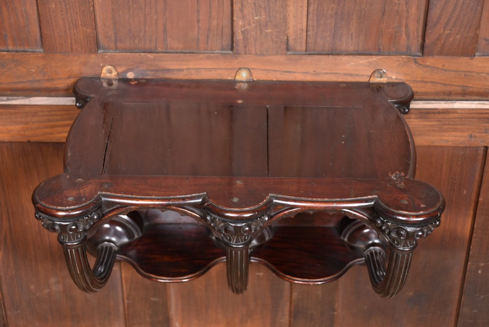 A Victorian dark rosewood carved wall bracket shelf featuring three fluted columns with carved capitals and scalloped arches. View IX