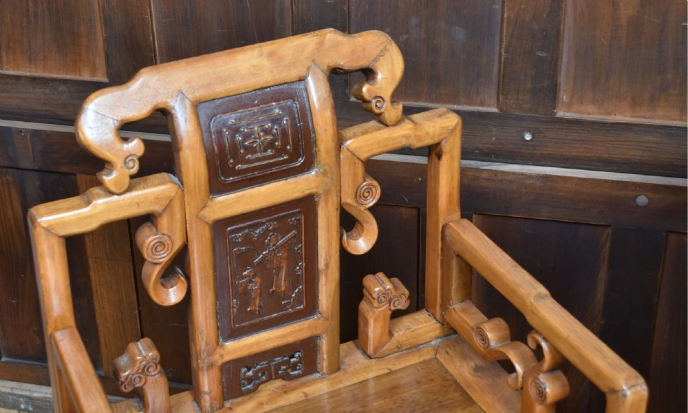 A pair of carved Chinese hardwood armchairs featuring decorative splats with darker wood relief panels and openwork arms. View VI