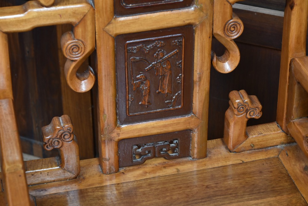 A pair of carved Chinese hardwood armchairs featuring decorative splats with darker wood relief panels and openwork arms. View VII