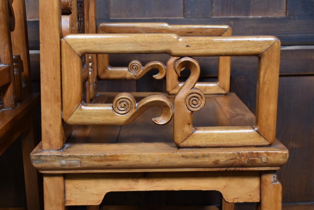 A pair of carved Chinese hardwood armchairs featuring decorative splats with darker wood relief panels and openwork arms. View XI