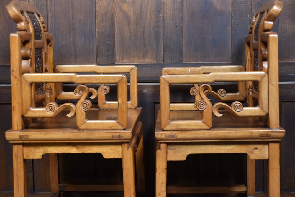 A pair of carved Chinese hardwood armchairs featuring decorative splats with darker wood relief panels and openwork arms. View XIV