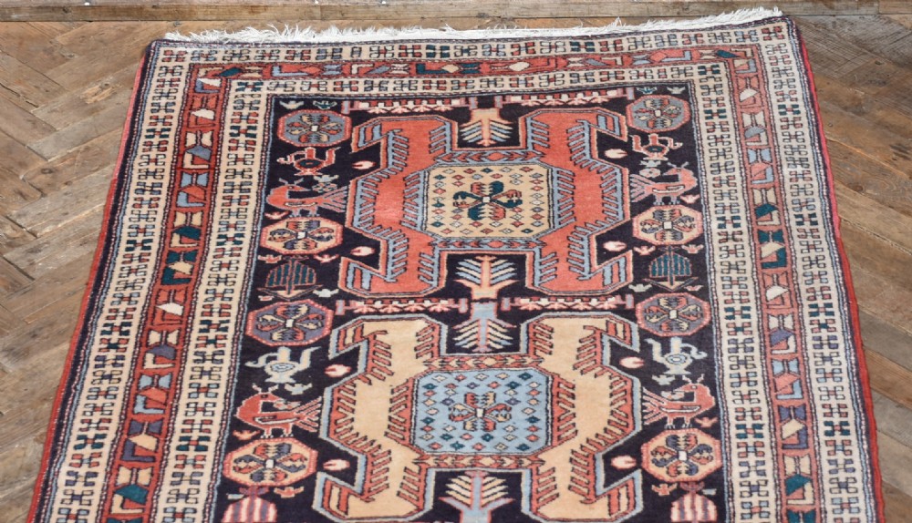 A hand-knotted wool runner rug featuring geometric medallions, bird motifs, and decorative borders in terracotta, cream, blue, and dark navy tones. View II