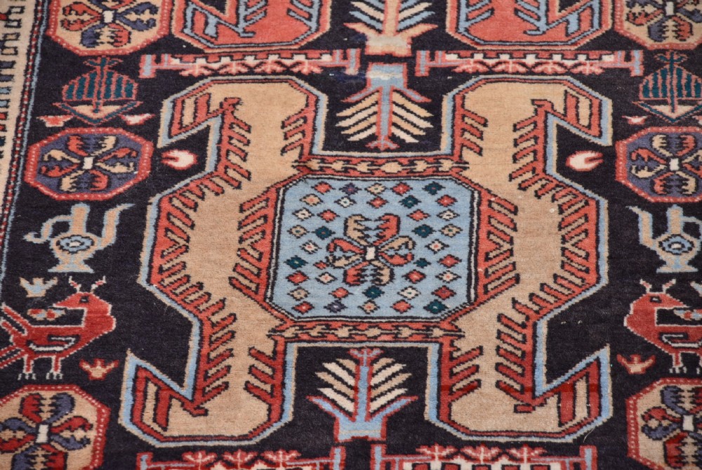 A hand-knotted wool runner rug featuring geometric medallions, bird motifs, and decorative borders in terracotta, cream, blue, and dark navy tones. View VIII
