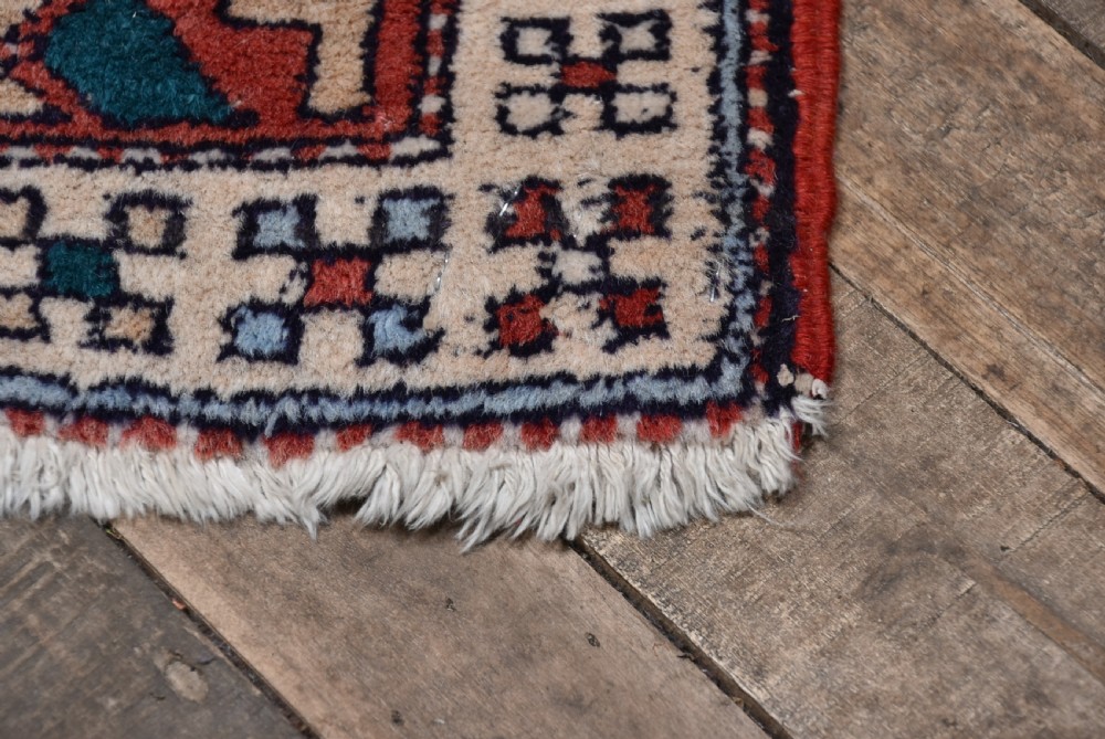 A hand-knotted wool runner rug featuring geometric medallions, bird motifs, and decorative borders in terracotta, cream, blue, and dark navy tones. View IX