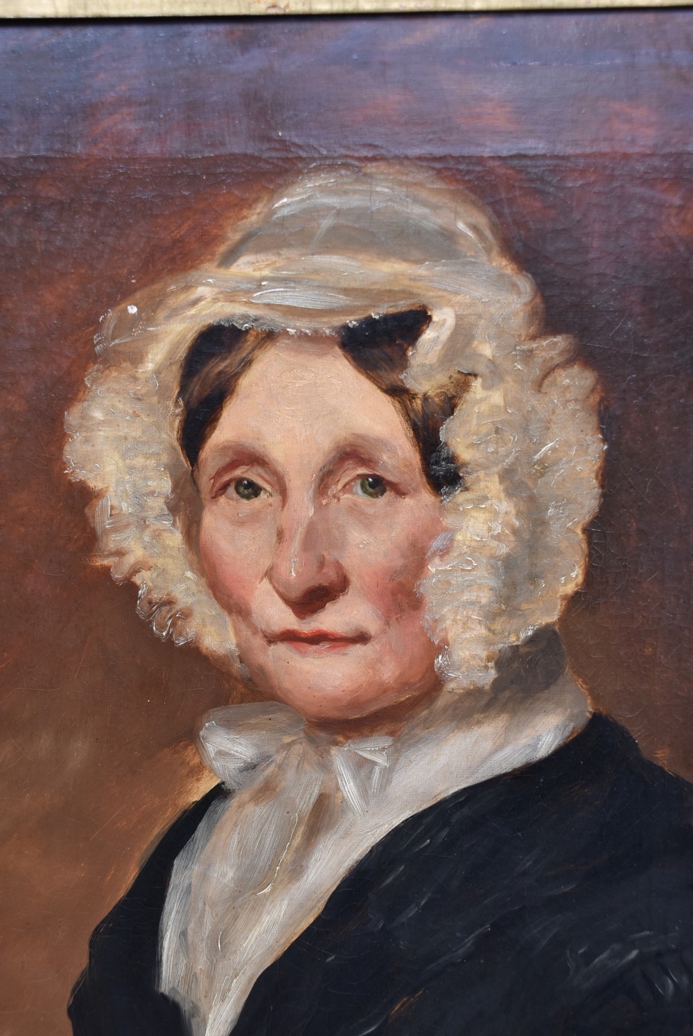An antique 19th-century oil portrait painting on canvas depicting an elderly woman wearing a lace bonnet, set inside a heavy ornate giltwood frame. View II