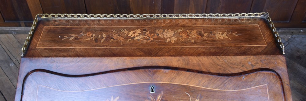 A Victorian marquetry bureau de dame desk featuring floral wood inlays, a slant front writing slope, pierced brass top gallery, and cabriole legs with brass mounts. View VII