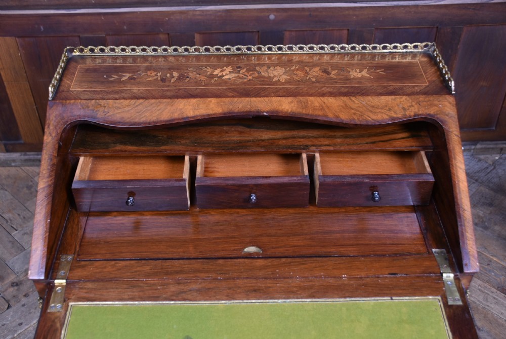 A Victorian marquetry bureau de dame desk featuring floral wood inlays, a slant front writing slope, pierced brass top gallery, and cabriole legs with brass mounts. View XIII